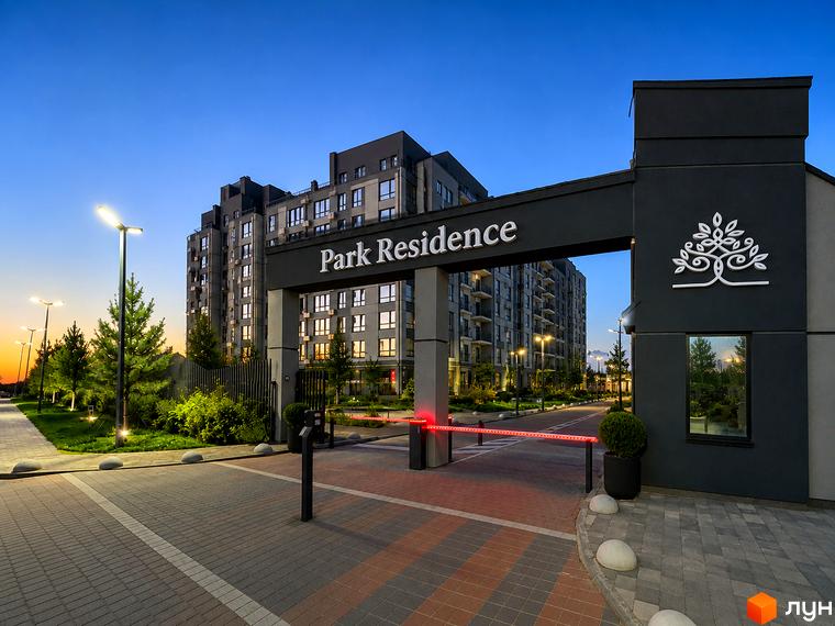 Житловий комплекс Park Residence з фасадами темних кольорів та підсвіченими вікнами. Територія перед комплексом освітлена ліхтарями та має зелені насадження.