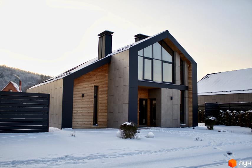 Котеджне містечко КМ Piemont eco village. Сучасний будинок з великими вікнами та дерев'яними елементами на тлі засніженої території.