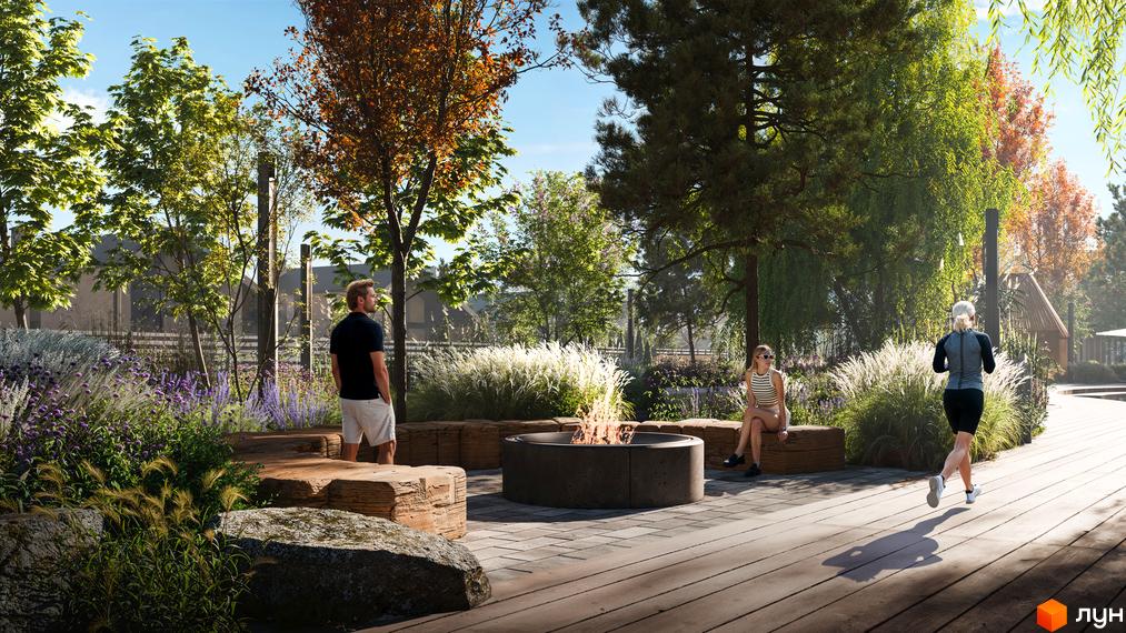 Котеджне містечко КМ Piemont eco village з зоною відпочинку біля вогнища та зеленими насадженнями. Люди відпочивають та займаються спортом на території комплексу.