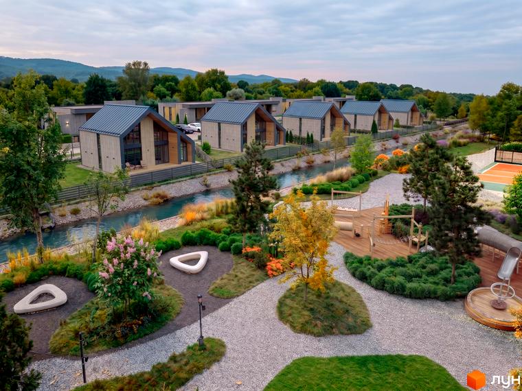 Котеджне містечко КМ Piemont eco village з сучасними будинками та доглянутою прибудинковою територією біля річки. На території є дитячий майданчик та зона відпочинку.