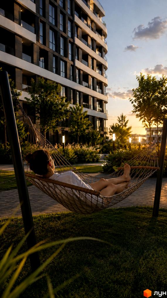 Будівельний проєкт SvitLand Residences з фасадом з темних панелей та білих елементів, поруч зелена зона з гамаком та деревами.