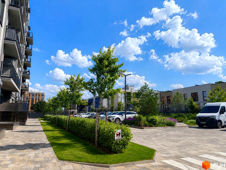 Житловий комплекс Park Residence з сучасними фасадами та доглянутою прибудинковою територією з деревами та газонами. Парковка для автомобілів та пішохідні доріжки.