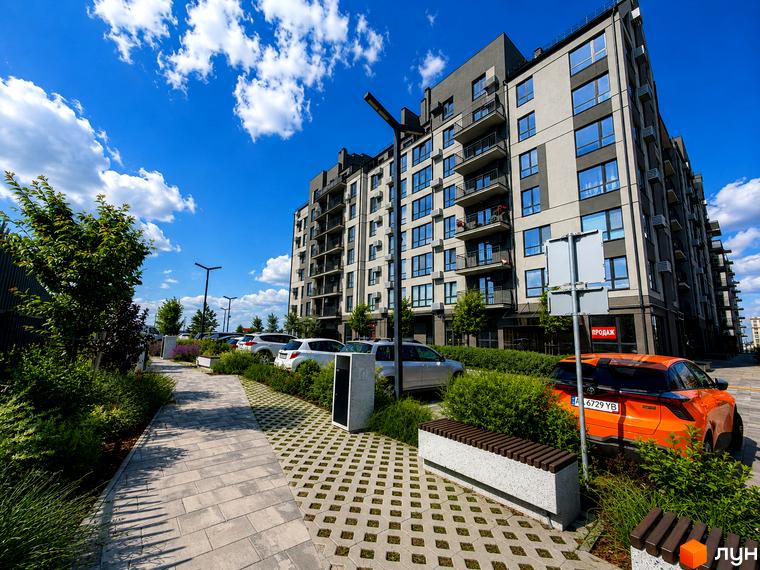 Житловий комплекс Park Residence з сіро-бежевим фасадом та балконами, поруч доглянута прибудинкова територія з пішохідною доріжкою та парковкою.