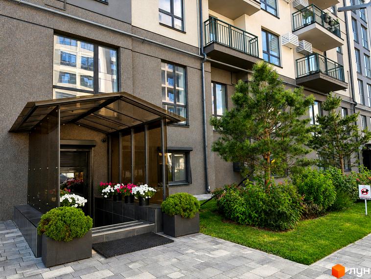 Житловий комплекс Park Residence: вхідна група з навісом, скляними дверима та квітами. Прибудинкова територія з зеленими насадженнями та газоном.