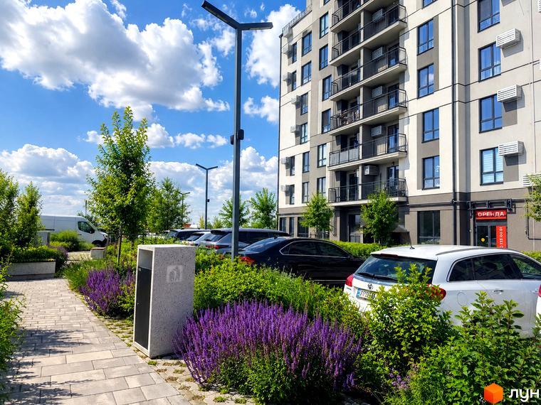 Фасад Житлового комплексу Park Residence з балконами та вікнами. Прибудинкова територія з квітами, зеленими насадженнями та автомобілями.