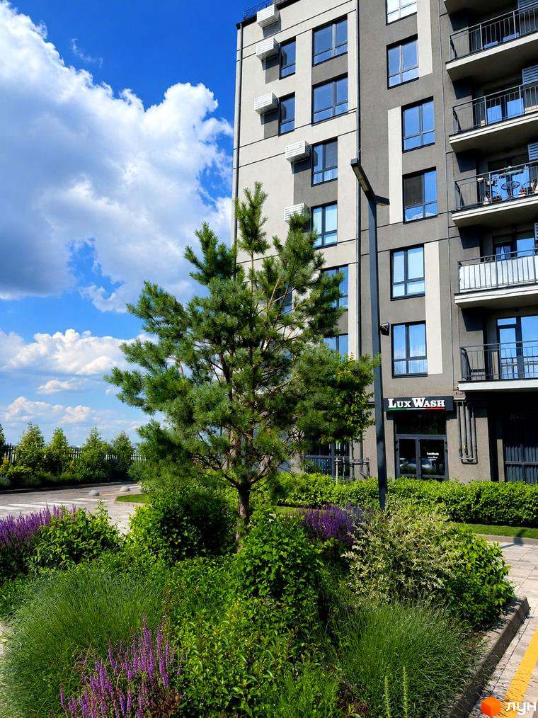 Багатоповерховий будинок Житлового комплексу Park Residence з сірим фасадом та балконами, оточений зеленими насадженнями.
