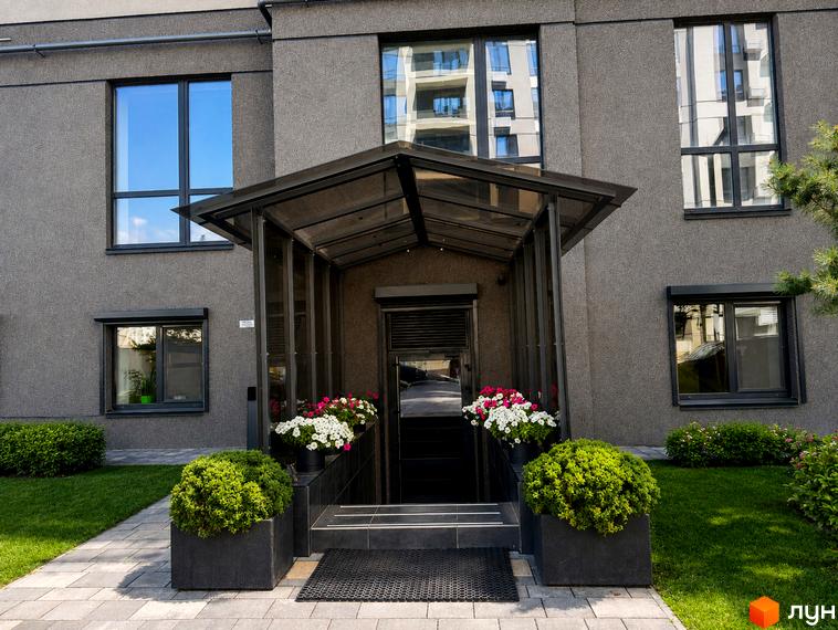 Житловий комплекс Park Residence: темно-сірий фасад, великі вікна, вхід під навісом, доріжка, зелені газони та квіти у вазонах.