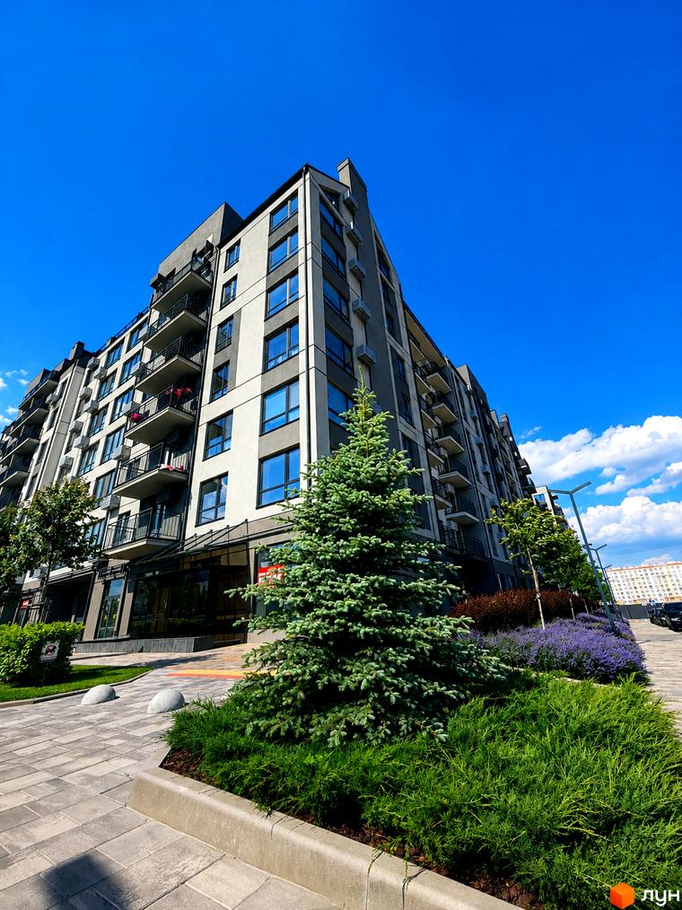Житловий комплекс Park Residence з сірими та білими фасадами, балконами та великими вікнами. Поруч зелені насадження, ялинка та лаванда.