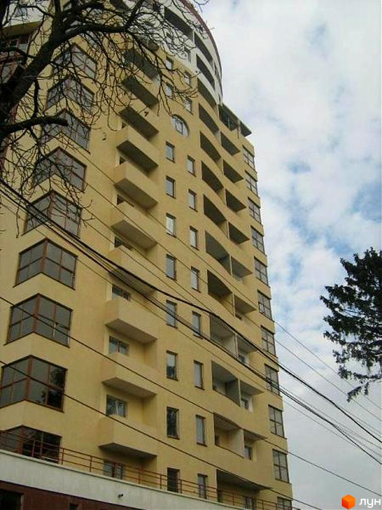 Житловий комплекс на вул. Льва Толстого, 9, має жовту фасадну обробку та балкони. Прибудинкова територія озеленена деревами.