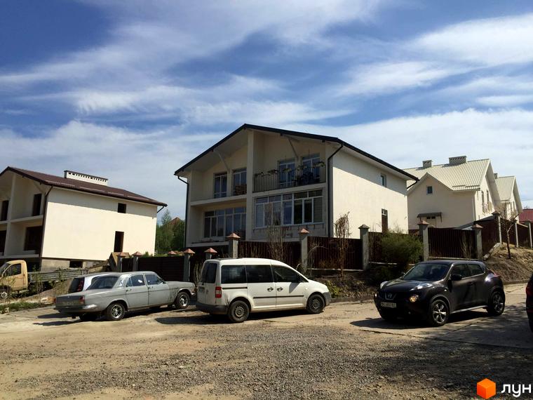 Котеджне містечко КМ Поршна-Наварія: сучасні будинки з балконами та паркуванням біля них. На території комплексу розташовані приватні будинки та паркувальні місця.