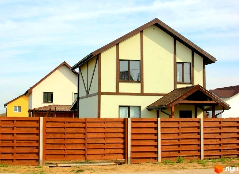 Котеджне містечко КМ Альпійський Хуторок. Зовнішній вигляд двоповерхових будинків з коричневим дахом та світлими стінами, огороджених дерев'яним парканом.
