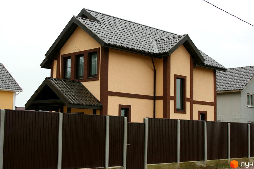 Котеджне містечко Альпійський Хуторок: двоповерховий будинок з бежевими стінами та темною черепицею. Огороджений темним парканом з бетонними стовпами.