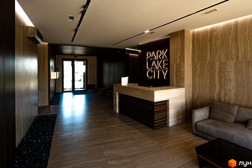 Лобі житлового комплексу Park Lake City з ресепшн та диваном. Вхідні двері з прозорими скляними вставками.