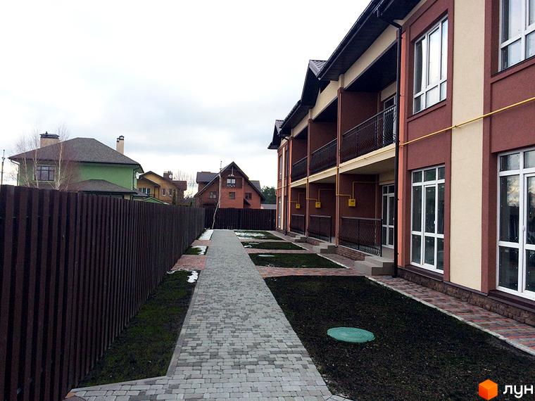 Таунхаус СанЛенд: двоповерхові будинки з балконами та великими вікнами. Поруч доглянута прибудинкова територія з бруківкою та зеленими насадженнями.