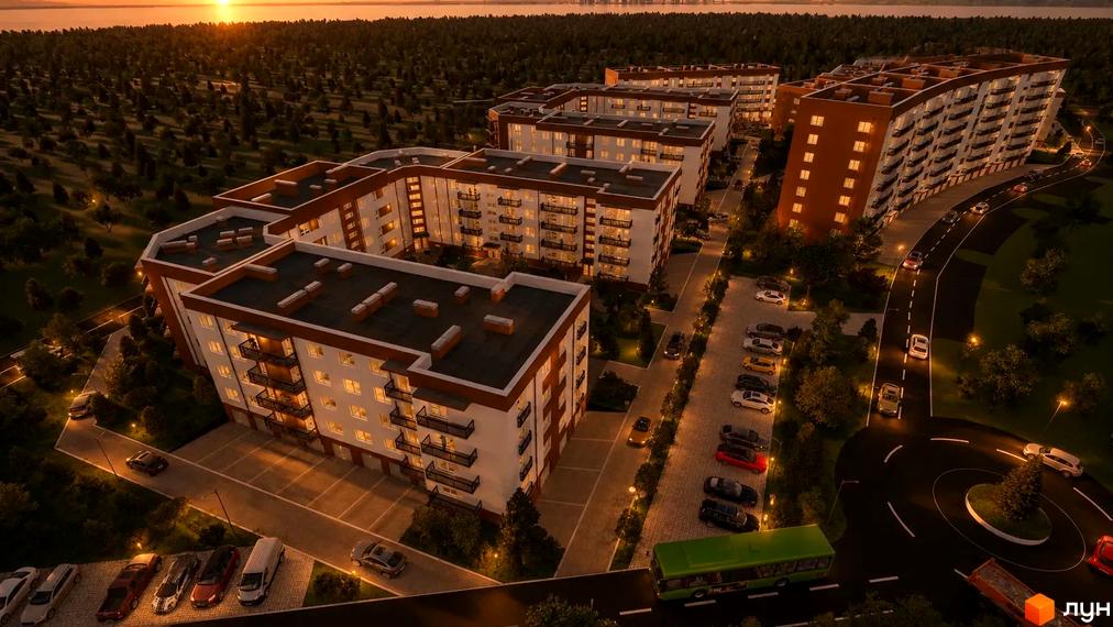 Житловий комплекс Family Life на заході сонця. Багатоквартирні будинки з білими фасадами, балконами, освітленими вікнами, серед зелені, доріг та парковок.