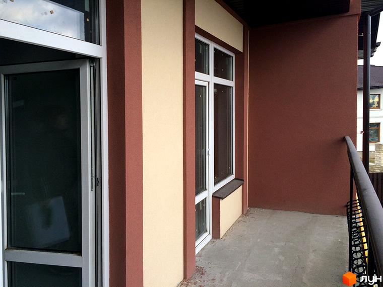 Зовнішній вигляд таунхаусу СанЛенд з білою рамою вікна та коричневими елементами фасаду. Балкон з металевою огорожею.