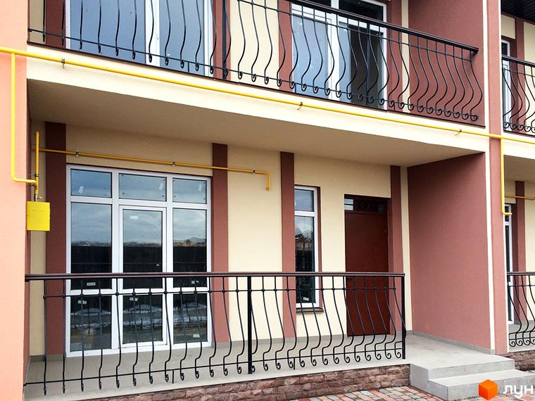 Зовнішній вигляд таунхаусів СанЛенд з балконами та вікнами. Навколо будівель розташована прибудинкова територія з газоном та елементами ландшафтного дизайну.