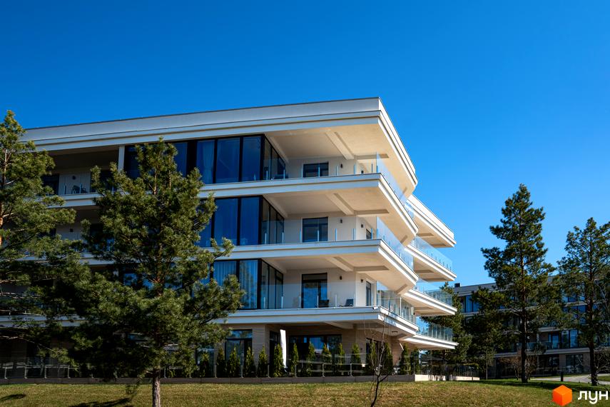 Житловий комплекс Park Lake City: багатоповерховий будинок з білими фасадами, великими вікнами та балконами. Навколо зелені сосни та газон.