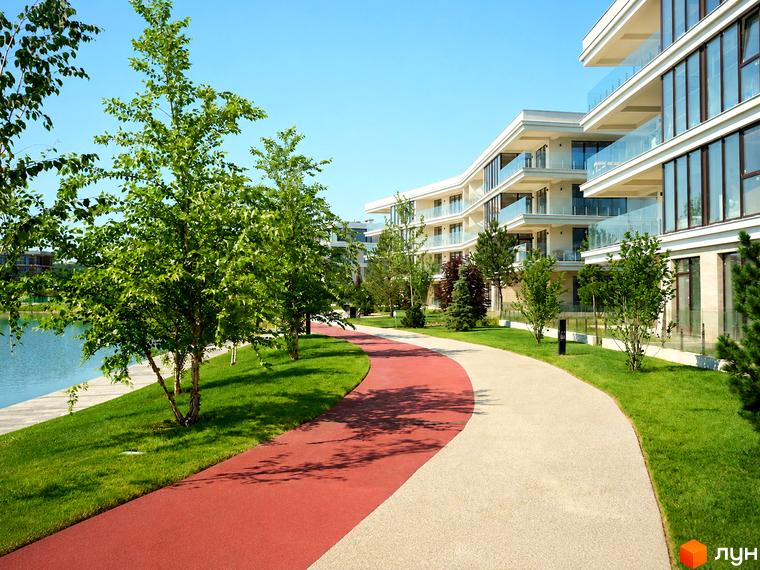 Житловий комплекс Park Lake City з білими фасадами та скляними балконами, оточений зеленою зоною та доглянутими доріжками біля озера.