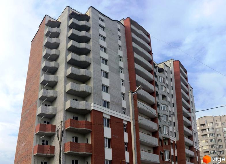 Зовнішній вигляд житлового комплексу Левада з цегляними та сірими фасадами, численними балконами та вікнами. Будинки розташовані на тлі хмарного неба.