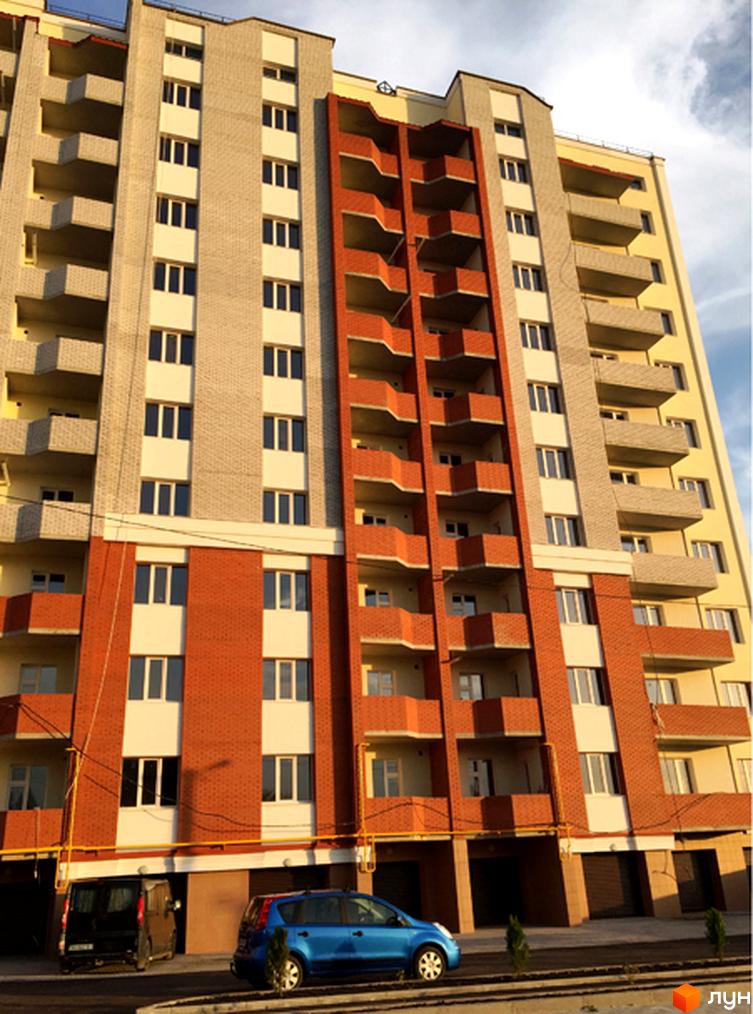 Житловий комплекс Левада - багатоповерховий будинок з червоно-бежевими фасадами та балконами. Біля будинку припарковані автомобілі.
