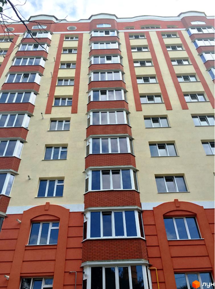 Фасад житлового комплексу Родинний затишок з жовтими та червоними елементами, великою кількістю вікон та балконів. Зовнішній вигляд новобудови.