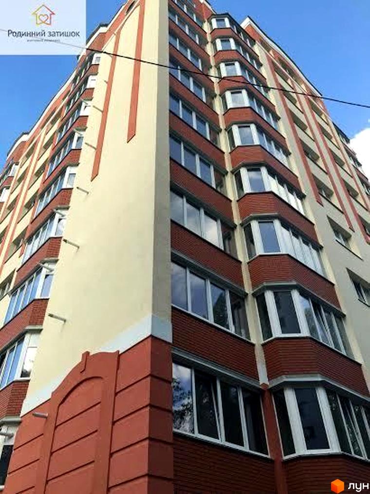 Новобудова ЖК Родинний затишок з фасадом кремового та червоного кольору. Будинок має багато вікон та балконів, розташований на фоні блакитного неба.