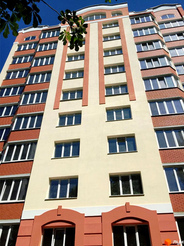 Зовнішній вигляд новобудови ЖК Родинний затишок з цегляним оздобленням фасаду та великою кількістю вікон. Будинок має багатоповерхову структуру з виразними архітектурними елементами.