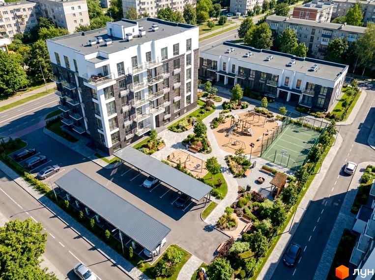Житловий комплекс Family space з біло-темними фасадами та балконами. Прибудинкова територія включає дитячий майданчик, спортивне поле та криті парковки.
