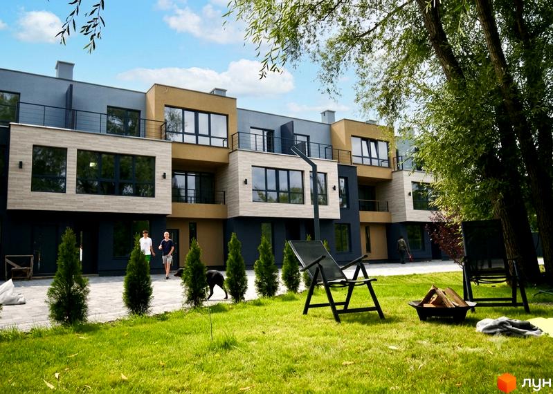 Таунхауси Rusaniv Gardens: багатоповерхові фасади сірого, бежевого та темно-сірого кольорів з великими вікнами. На території – зелений газон, доріжка та зона відпочинку.