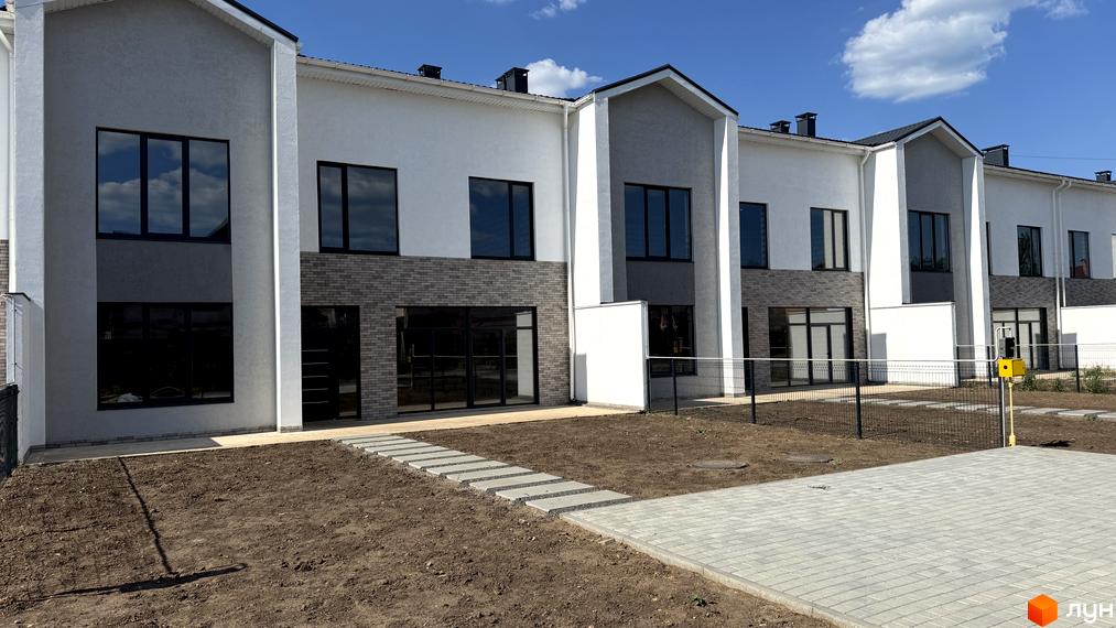 Таунхауси Lazur Village: двоповерхові будинки з білими, сірими фасадами та цегляною обробкою. Прибудинкова територія з ґрунтом і бруківкою.
