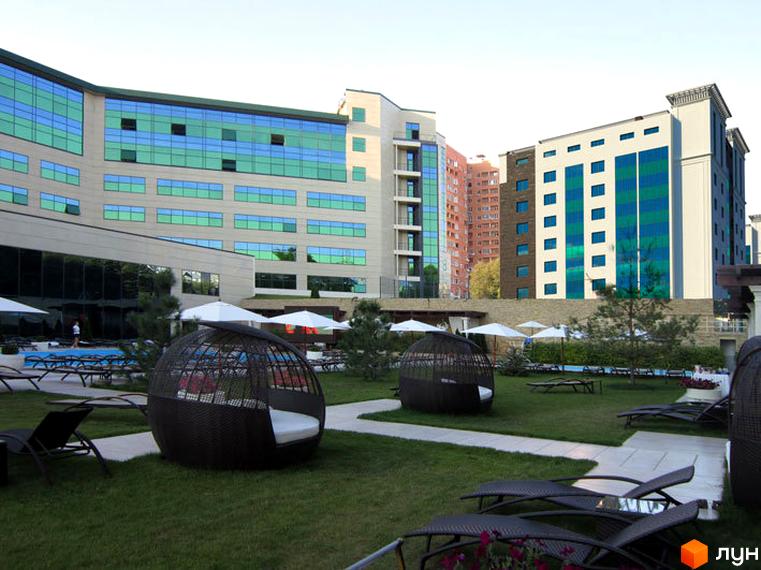 Зображення Житлового комплексу Ізумрудне місто з басейном та зоною відпочинку. Вигляд багатоповерхового будинку з великими вікнами та ландшафтним дизайном.