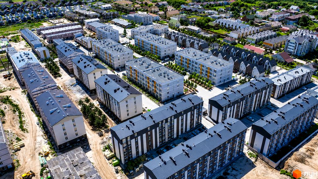 Житловий комплекс Sanville Park: аерофотографія будівель з темними та світлими фасадами, оточених зеленими насадженнями та дорогами.