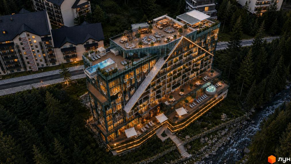 Багатоповерховий комплекс FERRO Premium Resort Bukovel зі скляними фасадами та терасами. Розташований у лісовій місцевості з річкою, має басейни та зони відпочинку на даху.