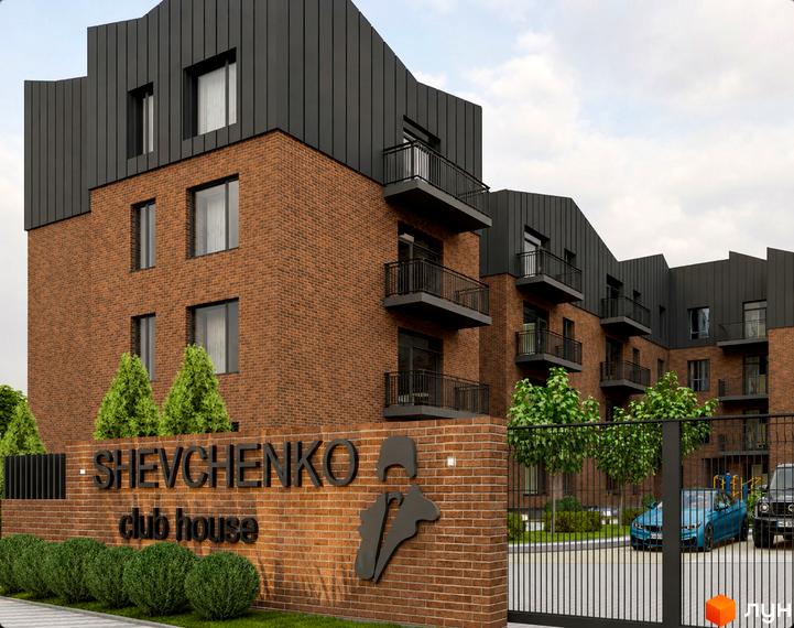 Клубний будинок SHEVCHENKO CLUB HOUSE з цегляним фасадом та темною покрівлею. На території комплексу видно зелені насадження, в'їзну браму та автомобілі.