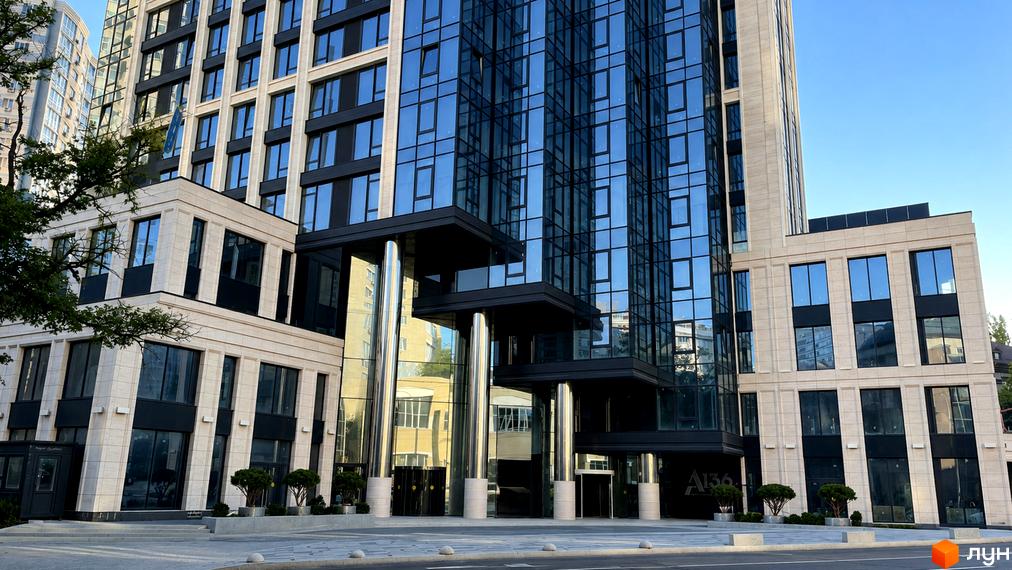 Зображення житлового комплексу A136 Highlight Tower, що показує багатоповерхову будівлю зі скляним фасадом та світлими панелями. Вхідна група має колони та прибудинкове озеленення.