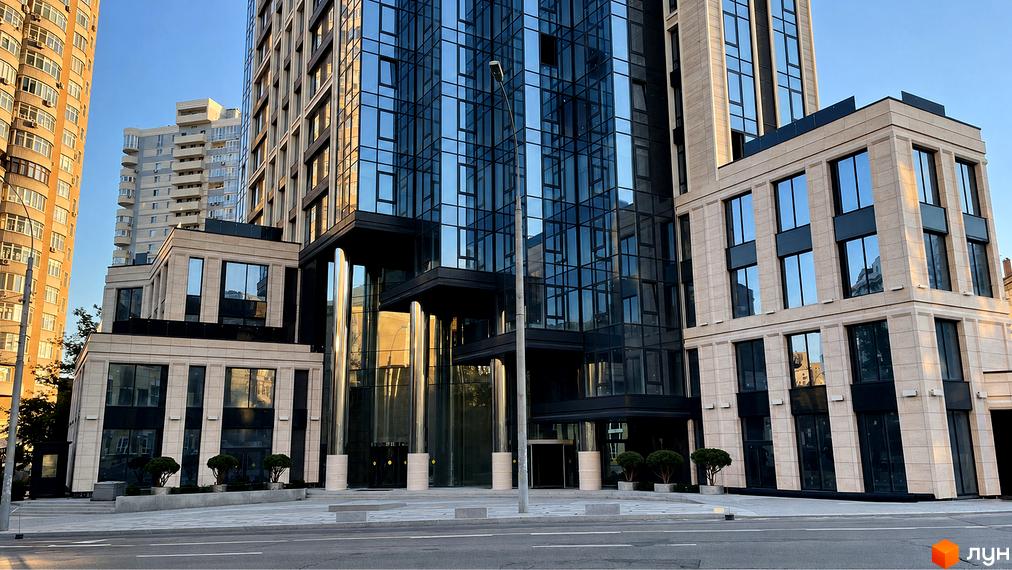 А136 Highlight Tower: висотна будівля зі скляним фасадом та світлими кам'яними елементами на нижніх поверхах, поруч з доглянутою прибудинковою територією.