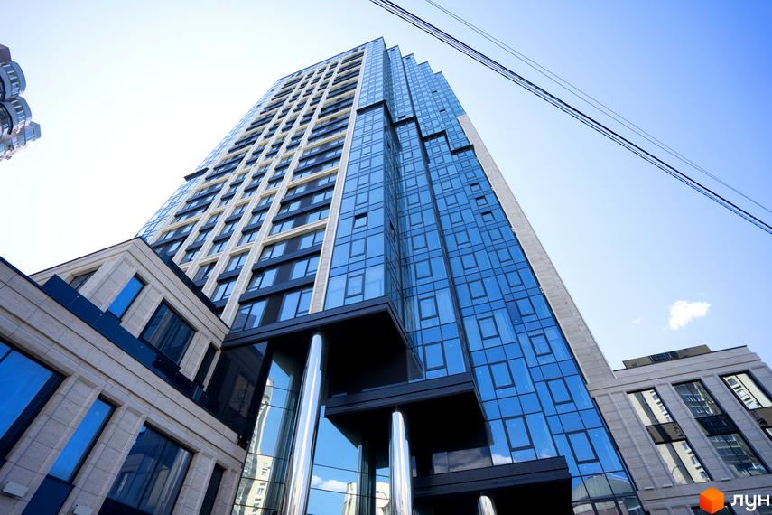 Житловий комплекс A136 Highlight Tower: висока будівля з блакитним скляним фасадом та світлими панелями, з архітектурними елементами біля основи.
