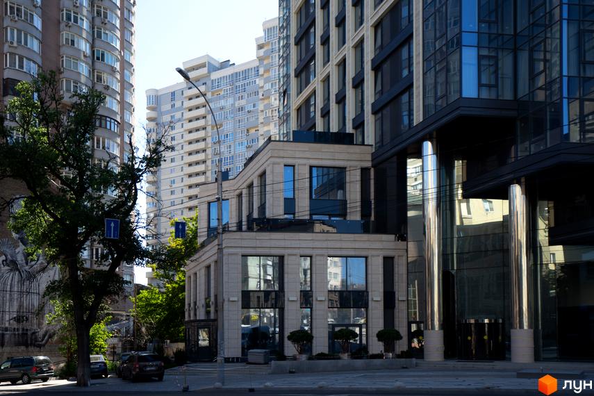 Багатоповерховий житловий комплекс А136 Highlight Tower зі світлим та темним фасадом, великими скляними вікнами та хромованими колонами біля входу.