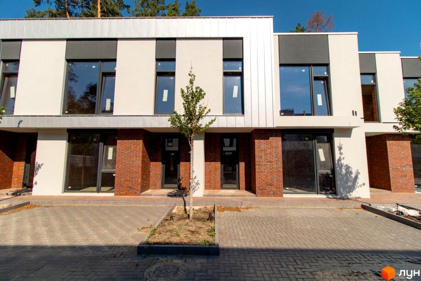Котеджне містечко КМ At HOME: фасади будинків з цегляними елементами та великими вікнами, вимощені бруківкою дворики.