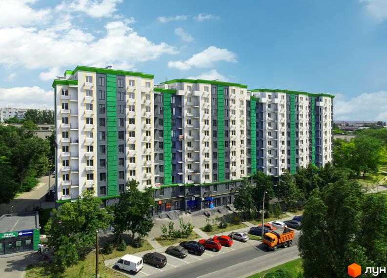 Новобудова Comfort City з яскравим фасадом та балконами, паркуванням та зеленими деревами навколо.