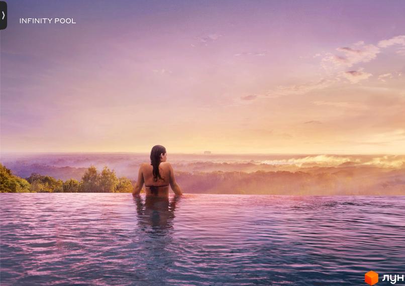 Infinity pool у Lion Hills Villas пропонує панорамний вид на лісовий масив та небо під час заходу сонця. Жінка відпочиває в басейні.