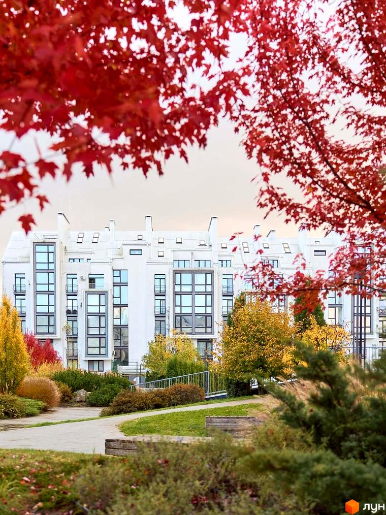 Житловий комплекс City Lake з білим фасадом та великими вікнами, оточений яскравими осінніми деревами та доріжками.