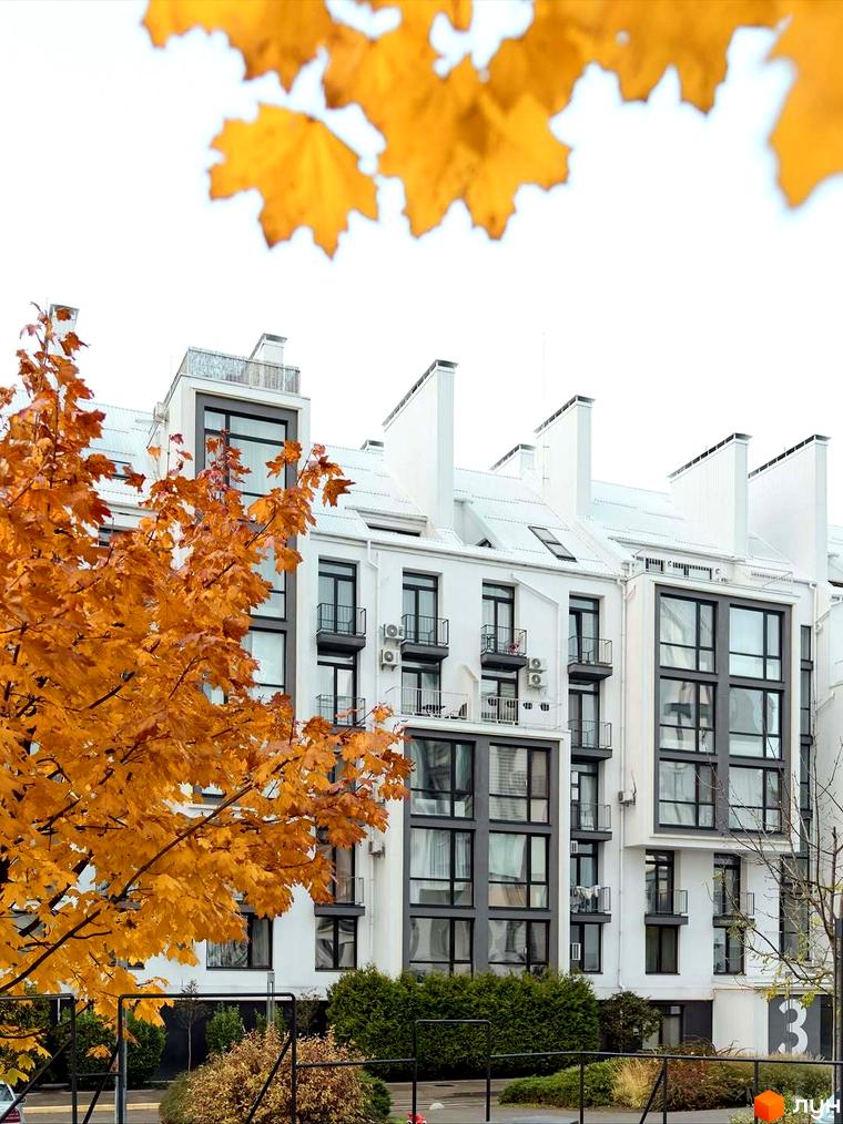 Житловий комплекс City Lake: білий багатоповерховий будинок з темними вікнами та балконами, оточений осінніми деревами та зеленими насадженнями.