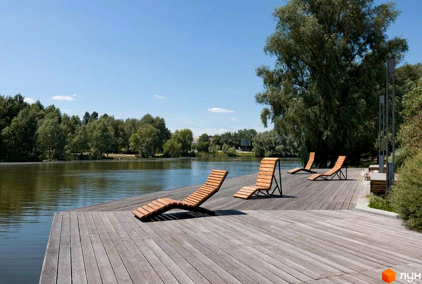 Житловий комплекс City Lake: дерев'яний настил з шезлонгами біля озера, оточений деревами, з блакитним небом.
