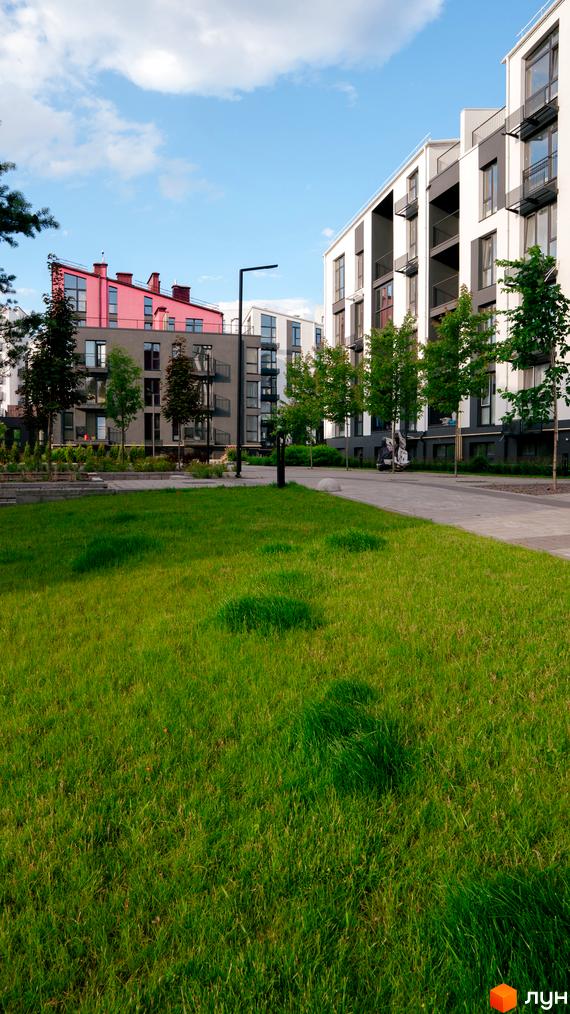 Житловий комплекс City Lake з яскраво-рожевими дахами та білими фасадами, зеленою галявиною та доглянутою прибудинковою територією.
