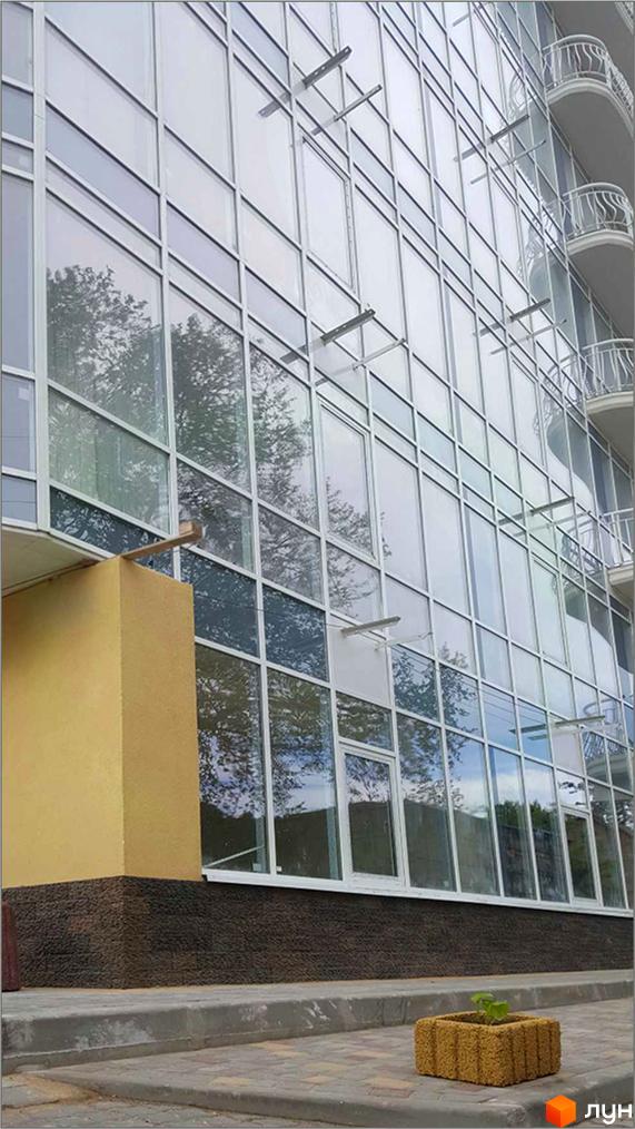 Зовнішній вигляд новобудови ЖК Париж з великими вікнами та балконами. На прибудинковій території видно зелені насадження.