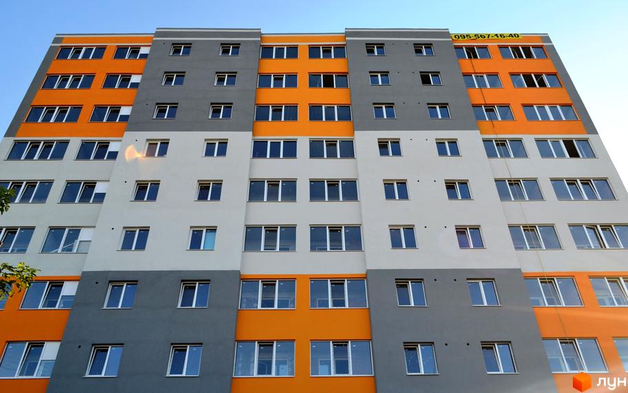 Зовнішній вигляд багатоповерхового будинку в Житловому комплексі Флагман. Фасад будинку пофарбований в сірий, білий та помаранчевий кольори.