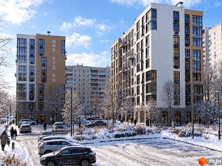 Фасад житлового комплексу TWINS RESIDENCE з панорамними вікнами та облаштована снігом прибудинкова територія.