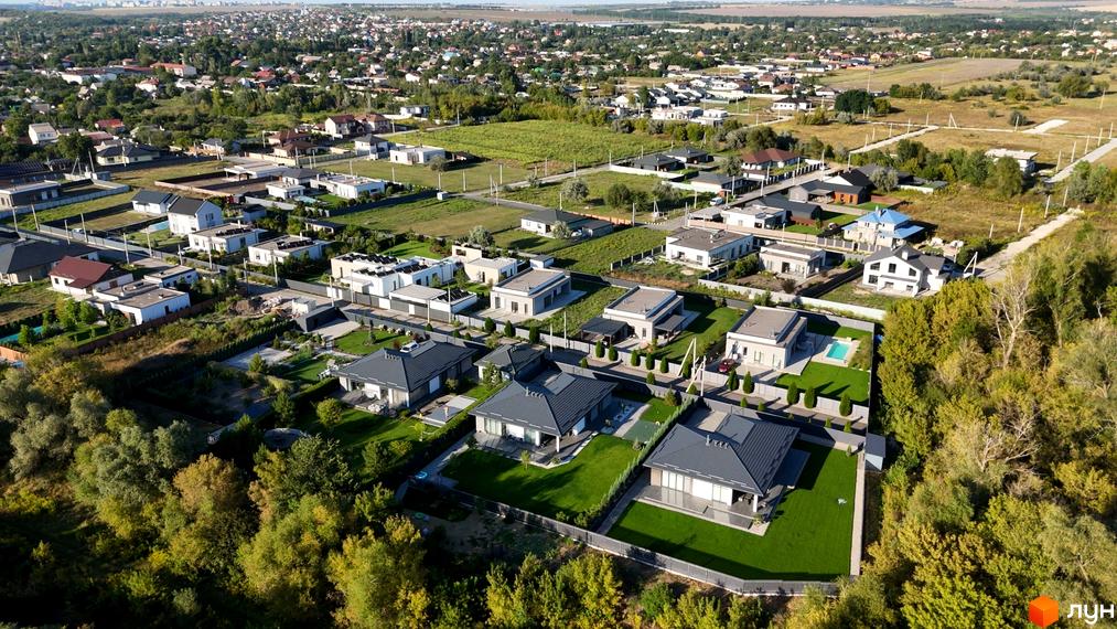 Будинки Котеджного містечка Sun Coast зі світлими фасадами та темними скатними дахами. Прибудинкова територія озеленена доглянутими газонами.